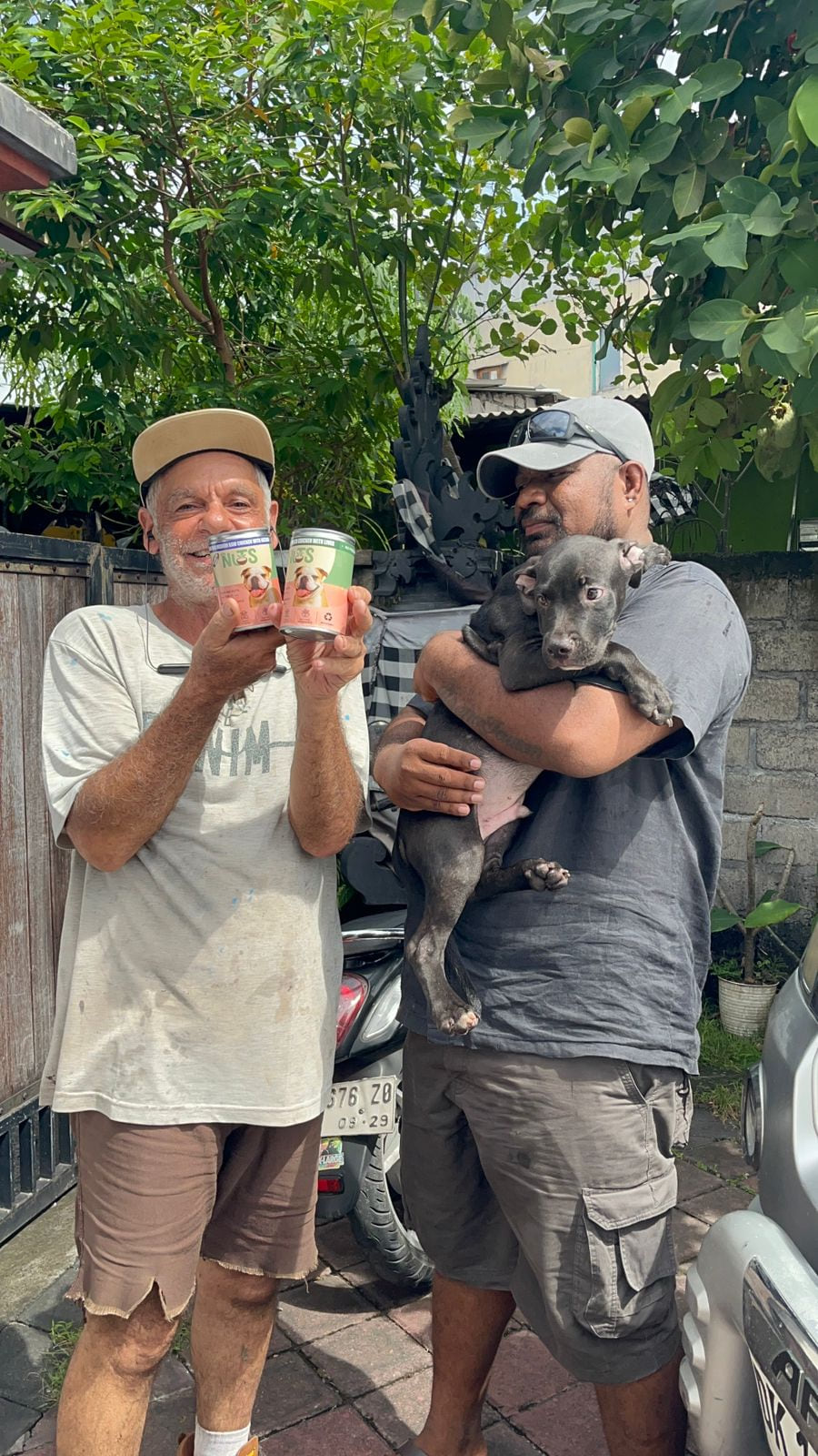 Avi holding two Nuts cans beside a customer holding a puppy in Bali